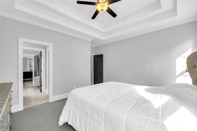 carpeted bedroom featuring baseboards, a tray ceiling, and ornamental molding