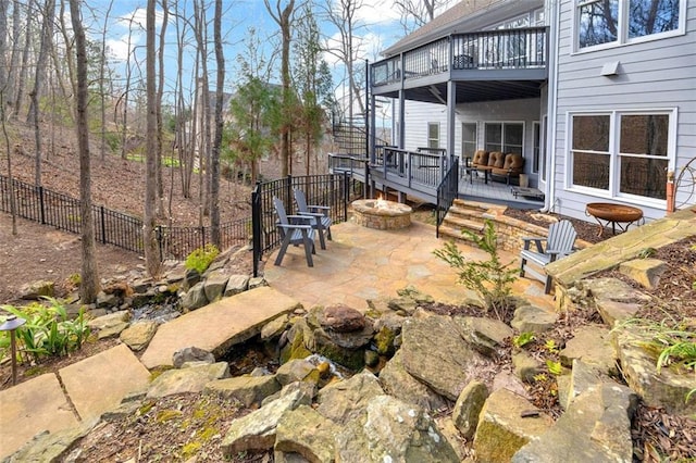 view of patio featuring a balcony, fence, a fire pit, and a wooden deck