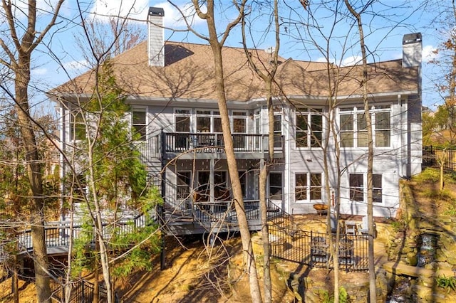 back of property with a deck, roof with shingles, fence, and a chimney