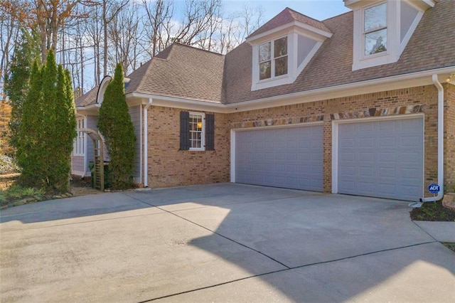 view of front of property with a garage, driveway, a shingled roof, and brick siding