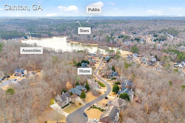 birds eye view of property featuring a water view and a wooded view