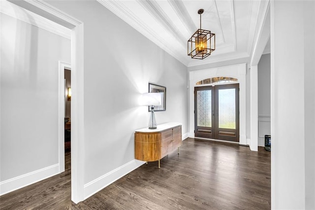 foyer with french doors, a notable chandelier, dark wood finished floors, ornamental molding, and baseboards