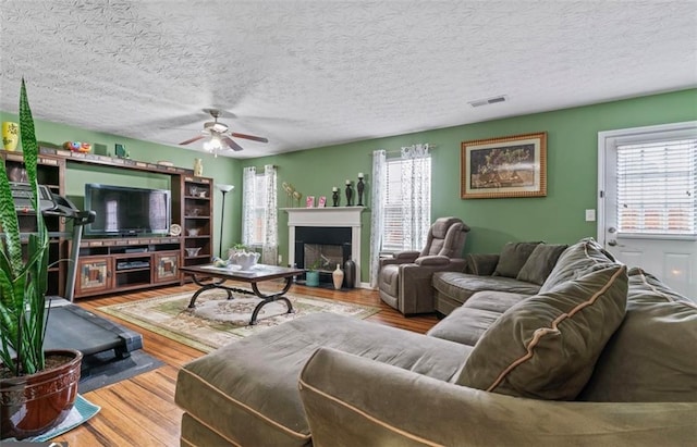 living room with hardwood / wood-style flooring, ceiling fan, and a textured ceiling