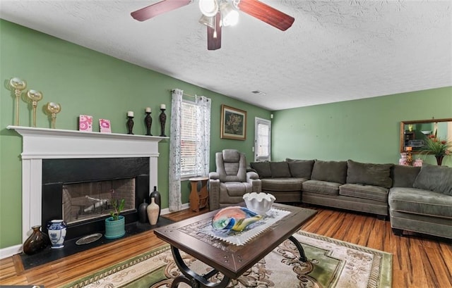 living room featuring wood-type flooring, ceiling fan, and a textured ceiling