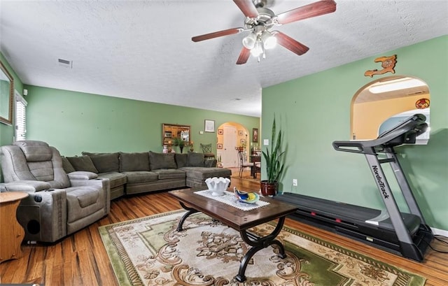 living room featuring hardwood / wood-style flooring, ceiling fan, and a textured ceiling