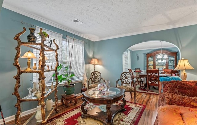 living area with crown molding, wood-type flooring, and a textured ceiling