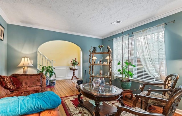 sitting room with crown molding, wood-type flooring, and a textured ceiling