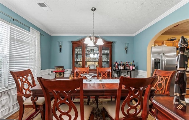 dining space featuring a notable chandelier, crown molding, a textured ceiling, and a healthy amount of sunlight