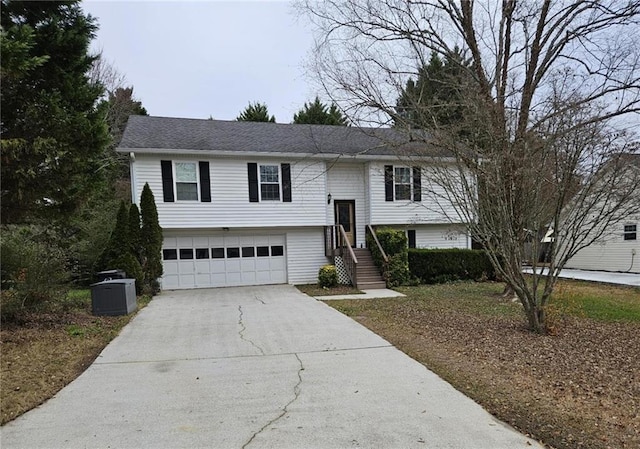 raised ranch with central air condition unit and a garage