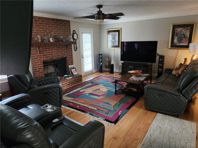 living room featuring a brick fireplace, a textured ceiling, ceiling fan, crown molding, and hardwood / wood-style flooring