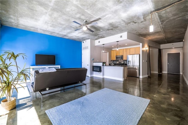 living room with finished concrete flooring, ceiling fan, visible vents, and baseboards