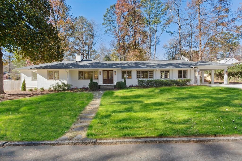 ranch-style house featuring a carport and a front lawn