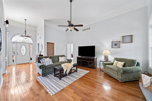 living room with visible vents, baseboards, ornamental molding, and light wood finished floors