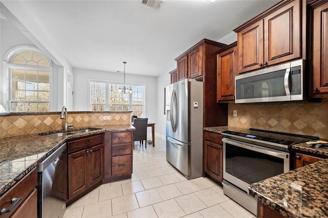 kitchen featuring visible vents, a sink, dark stone countertops, appliances with stainless steel finishes, and decorative backsplash