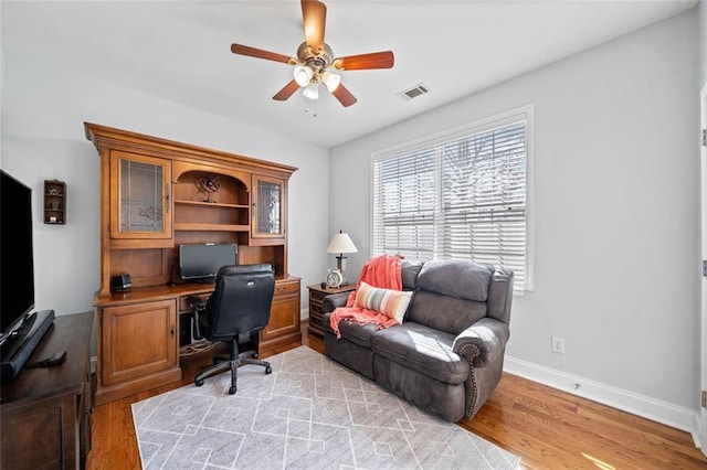 office space featuring visible vents, baseboards, a ceiling fan, and light wood finished floors