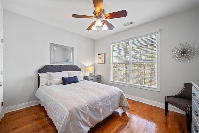 bedroom with visible vents, ceiling fan, baseboards, and hardwood / wood-style floors