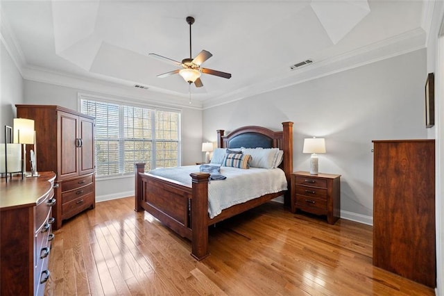 bedroom featuring visible vents, ornamental molding, light wood-style floors, baseboards, and ceiling fan