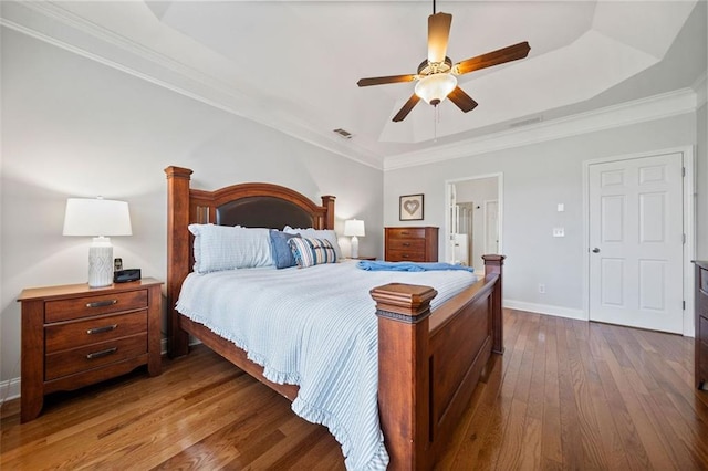 bedroom with dark wood-style floors, visible vents, baseboards, a tray ceiling, and crown molding