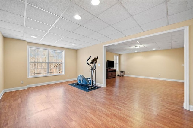 workout room with a paneled ceiling, baseboards, and wood finished floors