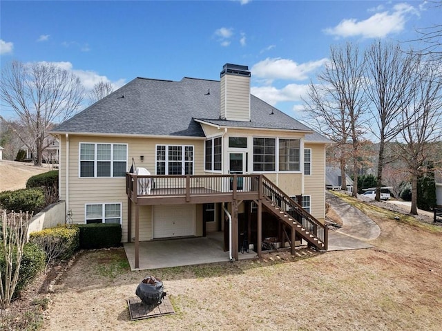 back of house featuring a shingled roof, stairway, a wooden deck, a chimney, and driveway