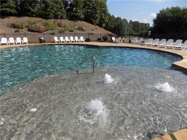 community pool with a patio area and fence