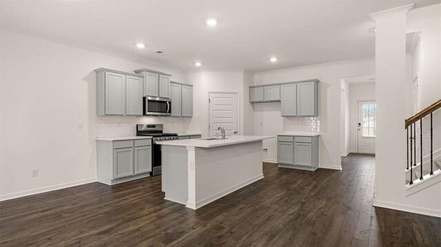 kitchen with appliances with stainless steel finishes, a kitchen island with sink, dark wood-type flooring, and gray cabinetry