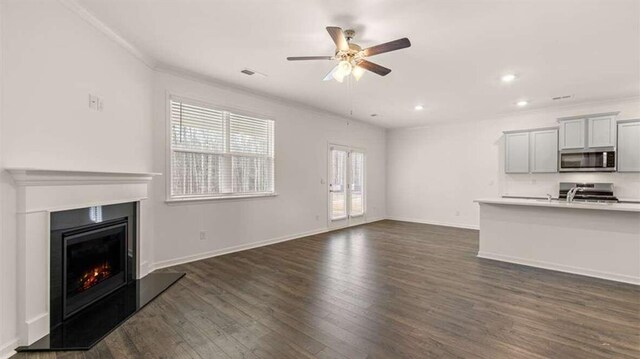 unfurnished living room with ornamental molding, ceiling fan, dark wood-type flooring, and sink