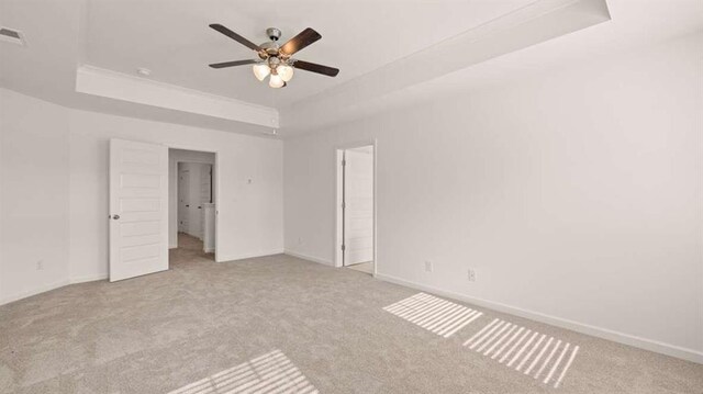 spare room featuring a tray ceiling, ceiling fan, and light colored carpet