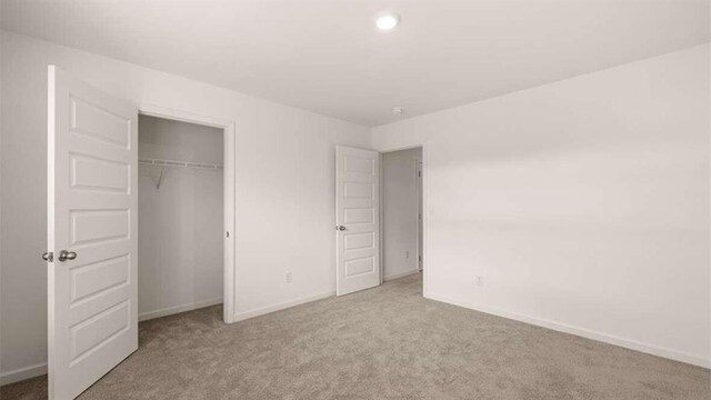 unfurnished bedroom with light colored carpet and a closet