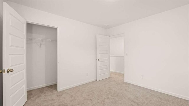 unfurnished bedroom with light carpet and a closet