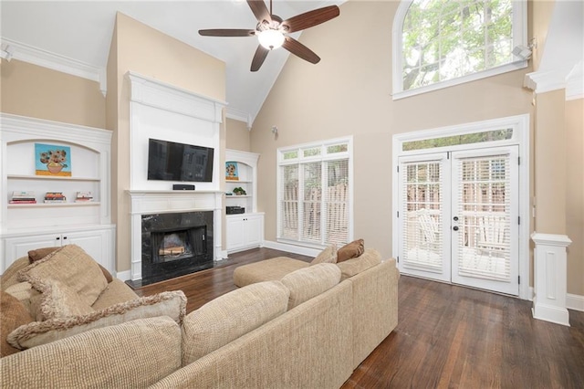 living room featuring ceiling fan, dark hardwood / wood-style floors, crown molding, a towering ceiling, and a fireplace