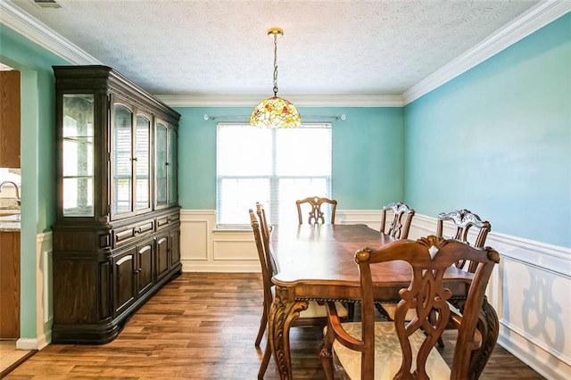 dining room featuring hardwood / wood-style floors, sink, ornamental molding, and a textured ceiling