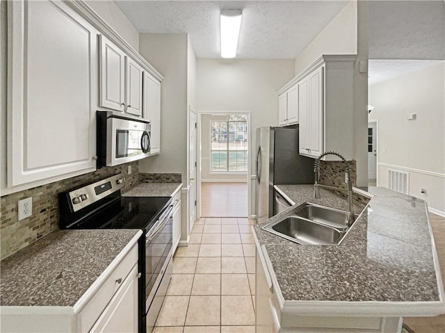 kitchen featuring decorative backsplash, sink, white cabinetry, light tile patterned floors, and appliances with stainless steel finishes