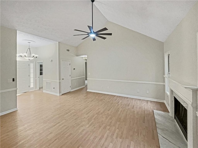 unfurnished living room with high vaulted ceiling, a textured ceiling, ceiling fan with notable chandelier, and light wood-type flooring