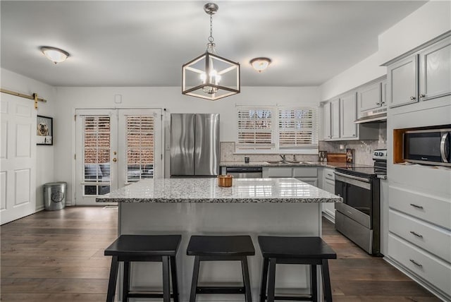 kitchen with a kitchen island, appliances with stainless steel finishes, a barn door, and decorative light fixtures