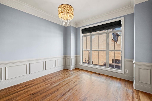 spare room with light hardwood / wood-style flooring, ornamental molding, and a notable chandelier