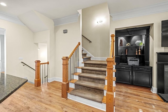 stairway with hardwood / wood-style flooring and ornamental molding