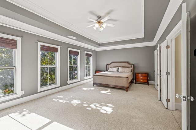 unfurnished bedroom featuring ceiling fan, ornamental molding, light carpet, and a tray ceiling