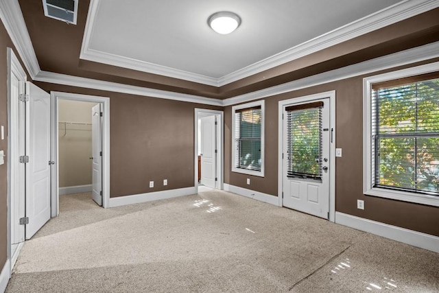 unfurnished bedroom with light carpet, a tray ceiling, and crown molding