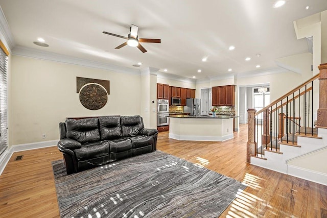 living room with ceiling fan, light wood-type flooring, and ornamental molding