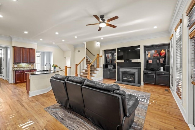 living room featuring ceiling fan, light hardwood / wood-style floors, ornamental molding, and sink