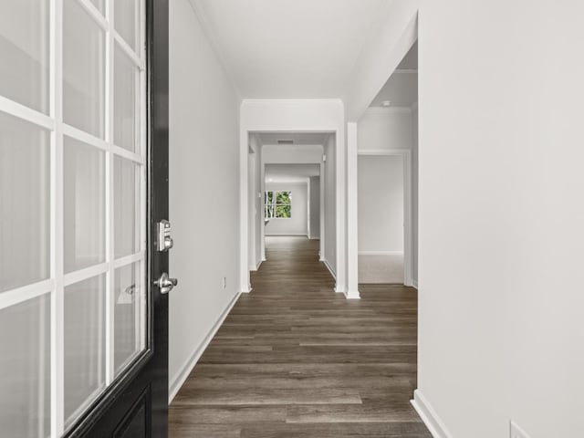 hallway with dark wood finished floors, baseboards, and ornamental molding