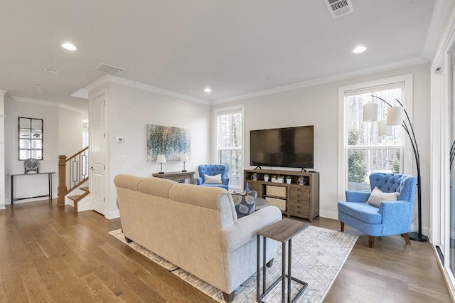 living room featuring stairway, visible vents, wood finished floors, and ornamental molding