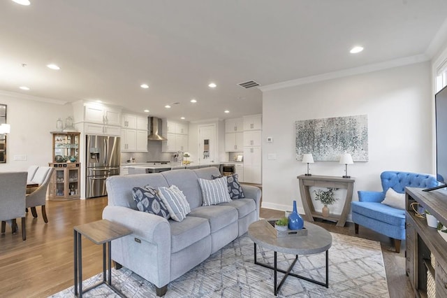 living room featuring visible vents, crown molding, and light wood finished floors