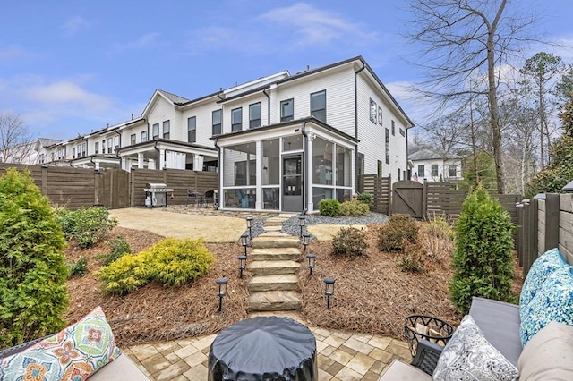 back of property featuring a patio, a fenced backyard, a gate, and a sunroom