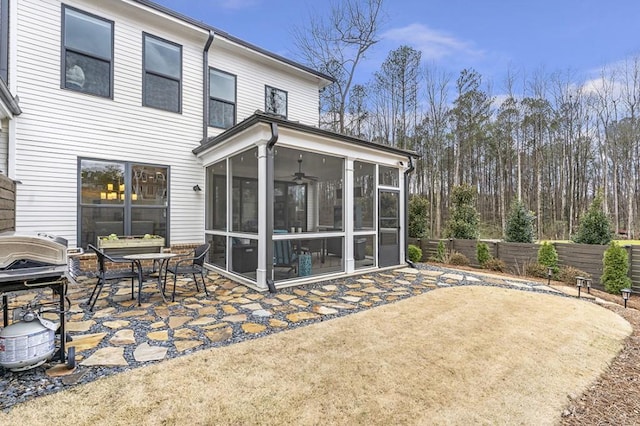 rear view of house with a sunroom, a patio area, and fence