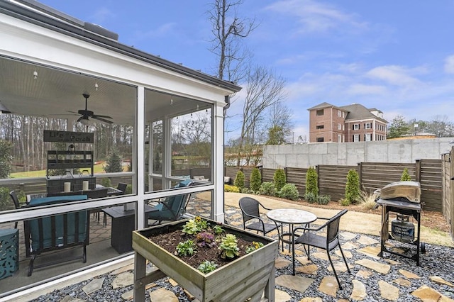 view of patio with grilling area, fence, and a sunroom