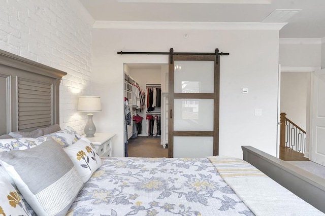 bedroom with a closet, crown molding, a spacious closet, and a barn door