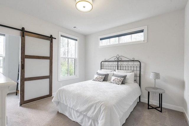 bedroom featuring carpet floors, visible vents, multiple windows, and a barn door