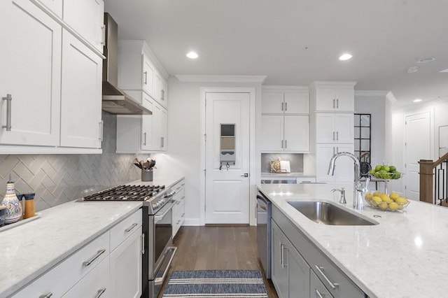 kitchen with wall chimney exhaust hood, appliances with stainless steel finishes, ornamental molding, dark wood-style flooring, and a sink